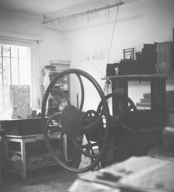 A workshop with a press in the foreground.