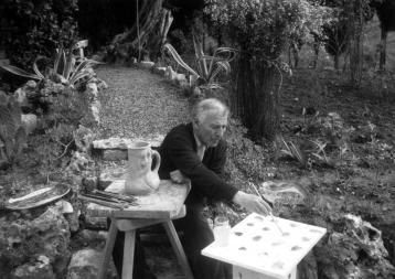 Marc Chagall painting a vase, in the middle of a garden