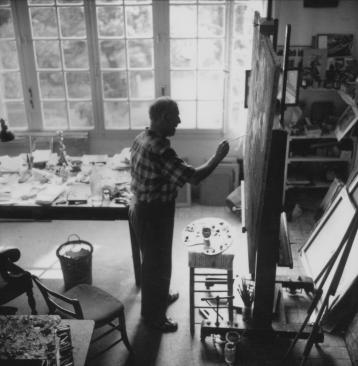 Marc Chagall peignant dans un atelier à grandes fenêtres donnant sur un jardin.