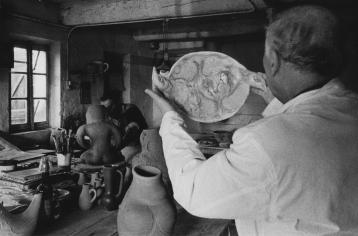 Marc Chagall holding with both hands a painted ceramic in the shape of a bird.