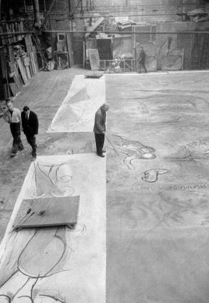 Chagall standing, working with a long paintbrush on a stage curtain for the ballet Daphnis and Chloé.