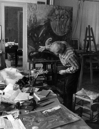 Chagall leaning,  in front of the painting Jacob's dream on an easel.