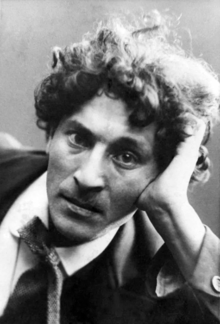 Portrait de Marc Chagall, jeune, les cheveux bouclés et le visage appuyé sa main.
