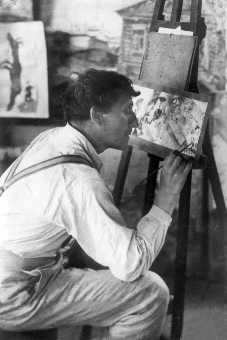 Marc Chagall, jeune, travaille au pinceau fin les détails de l'Etude pour l'Introduction au théâtre d'Art juif.